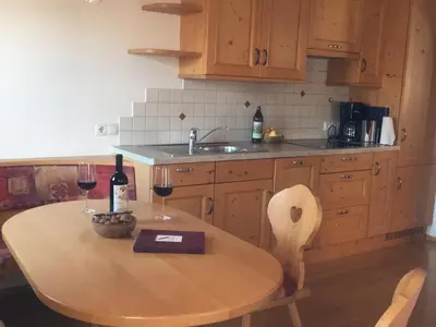 a kitchen with a wooden table with two glasses of wine at Lafreiderhof in Castelrotto