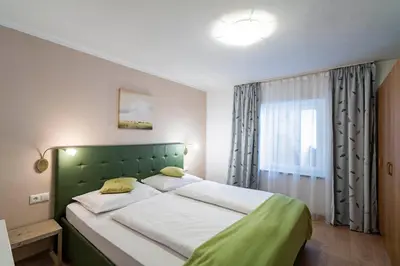 a bedroom with a large bed with a green headboard at Residence Alpina in Tesimo