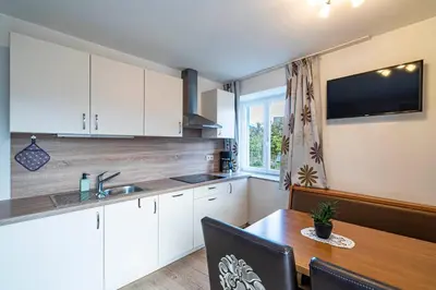 a kitchen with white cabinets and a wooden table at Residence Alpina in Tesimo