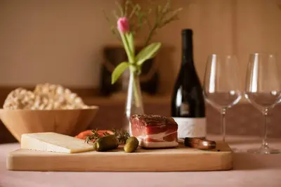 a wooden cutting board with cheese and a bottle of wine at Garni-Hotel mir.es in Tirolo