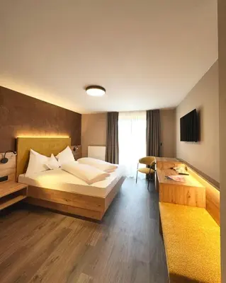 a hotel room with a bed and a desk at Garni-Hotel mir.es in Tirolo