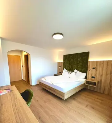 a bedroom with a large white bed and a table at Garni-Hotel mir.es in Tirolo
