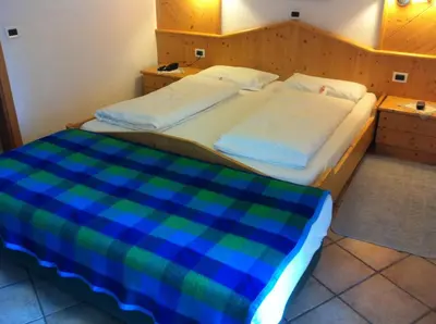 a bedroom with two beds with a blue and green blanket at Piccolo Hotel Sciliar in Alpe di Siusi