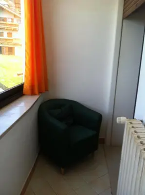 a black chair sitting in a corner next to a window at Piccolo Hotel Sciliar in Alpe di Siusi
