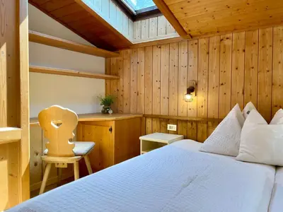 a bedroom with a white bed and a chair at Chalet Forciagn in San Vigilio Di Marebbe