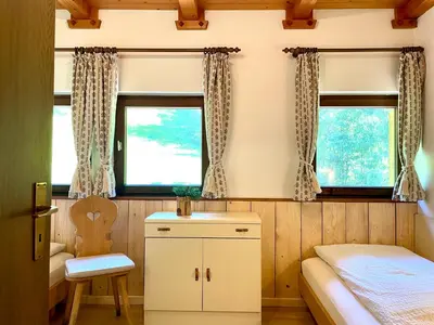 a small bedroom with a bed and two windows at Chalet Forciagn in San Vigilio Di Marebbe