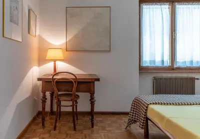 a bedroom with a desk with a chair and a lamp at Dolomites White Rest - Mountain View in Tres