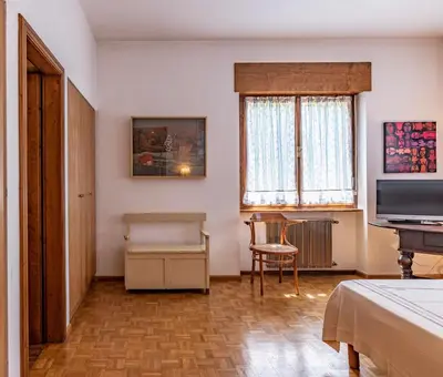 a room with a bed and a television and a chair at Dolomites White Rest - Mountain View in Tres