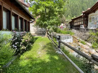 a yard next to a house with a fence and flowers at Dolomites Holiday Home in Canazei