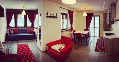 a living room with a red chair and a table at Dolomites Holiday Home in Canazei