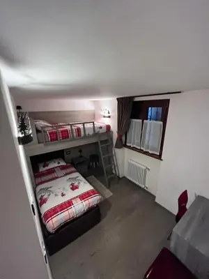 a small room with a bed and a staircase at Dolomites Holiday Home in Canazei
