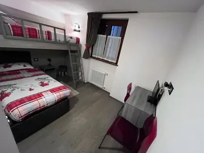 a bedroom with a bed and a chair in it at Dolomites Holiday Home in Canazei