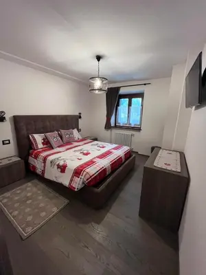 a bedroom with a bed and a television in it at Dolomites Holiday Home in Canazei