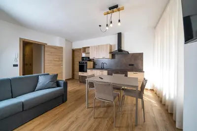 a living room with a couch and a table and a kitchen at Cauriol Suites 1.1 in Cavalese