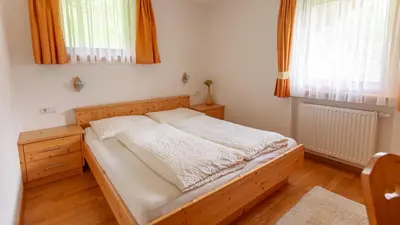a bedroom with a wooden bed and two windows at Pretzerhof in Campo di Trens