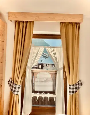a window with curtains in a room at Eurochalet in Campitello di Fassa