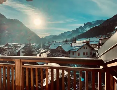 a view from a balcony of a town with snow covered mountains at Eurochalet in Campitello di Fassa