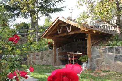 a wooden shelter in a garden with red flowers at Apartment Weissenegger in Fiè