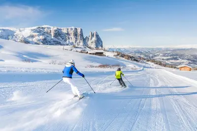 two people are skiing down a snow covered slope at Apartment Weissenegger in Fiè