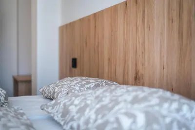 a bed with two pillows and a wooden head board at Cauriol Suites 2.3 in Cavalese
