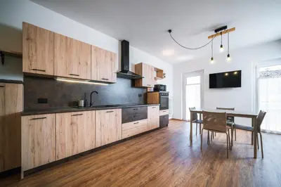 a kitchen with wooden cabinets and a dining table at Cauriol Suites 2.3 in Cavalese