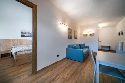 a living room with a blue couch and a mirror at Cauriol Suites 2.3 in Cavalese