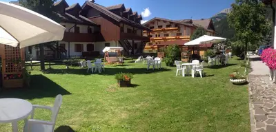 a group of tables and chairs in a yard with buildings at Park Hotel Mater Dei in Pozza di Fassa