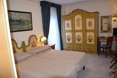 a bedroom with two beds and a table and a desk at Park Hotel Mater Dei in Pozza di Fassa