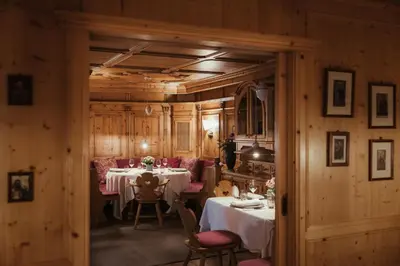 a dining room with two tables and pink chairs at Kolfuschgerhof Mountain Resort in Colfosco