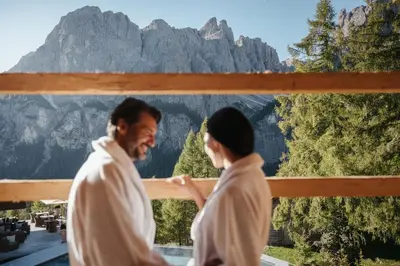 a man and a woman walking in front of a mountain at Kolfuschgerhof Mountain Resort in Colfosco