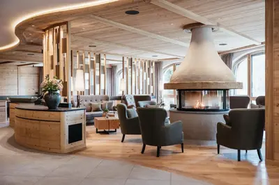 a lobby with chairs and a fireplace in a room at Kolfuschgerhof Mountain Resort in Colfosco