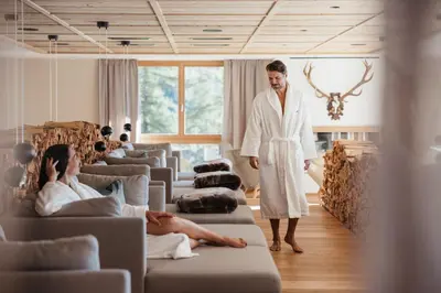 a man standing in a room with a woman laying on a couch at Kolfuschgerhof Mountain Resort in Colfosco