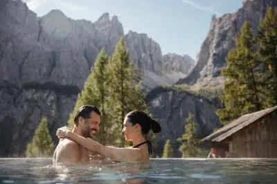 a man and woman in the water in the mountains at Kolfuschgerhof Mountain Resort in Colfosco