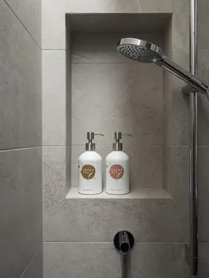 two bottles ofodorizers sitting on a shelf in a shower at Arieshof in Floronzo