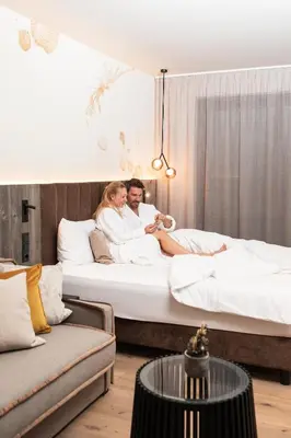 a man and a woman sitting on a bed at Arieshof in Floronzo