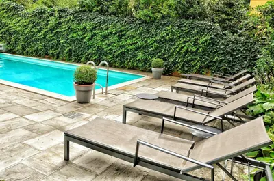 a group of chairs sitting next to a swimming pool at Hotel Zima in Merano