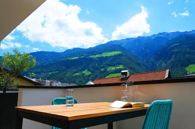 a table on a balcony with a view of mountains at Apartment Oleander - Alpstay in Naturno