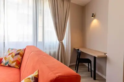 a room with a couch and a desk and a window at Apartments Iris in Merano