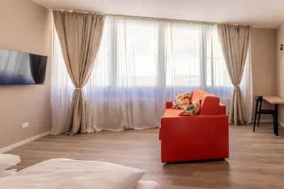 a living room with a red chair in front of a window at Apartments Iris in Merano