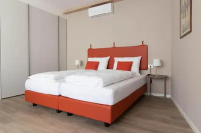 a red bed with white sheets and red pillows at Apartments Iris in Merano