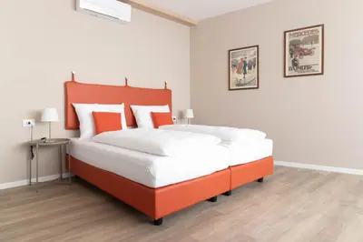 a bedroom with a large bed with an orange headboard at Apartments Iris in Merano