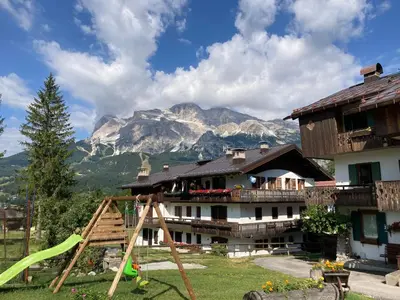 a house with a playground in front of a mountain at Appartamento Cortina d'Ampezzo Lovely Hearts in Cortina dʼAmpezzo