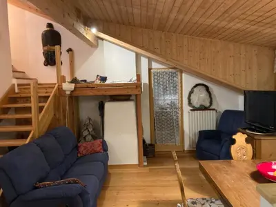 a living room with a blue couch and a loft at Appartamento Cortina d'Ampezzo Lovely Hearts in Cortina dʼAmpezzo