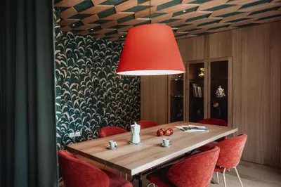 a dining room table with red chairs and a red lamp at Der Mittermoar in Bressanone