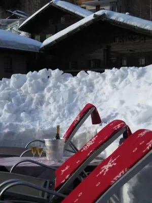 a pile of snow with a table with a bottle of champagne at Gasthof Eggwirt in Ultimo