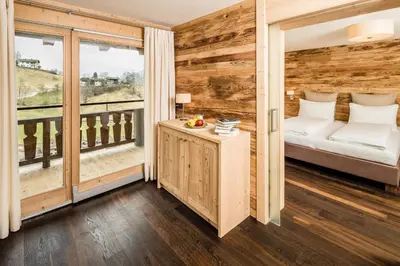 a room with a wooden wall with a bed and a balcony at Gasthof Eggwirt in Ultimo