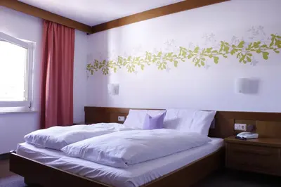 a bedroom with a large bed with white sheets at Zur Mühle in Ora/Auer