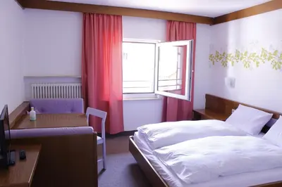 a bedroom with a bed and a desk and a window at Zur Mühle in Ora/Auer