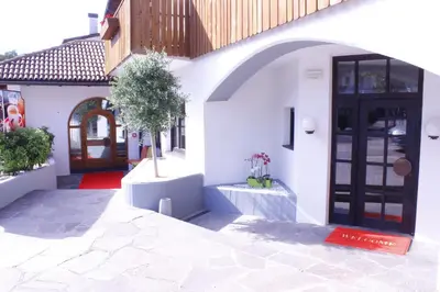 a white building with a black door and a tree at Zur Mühle in Ora/Auer