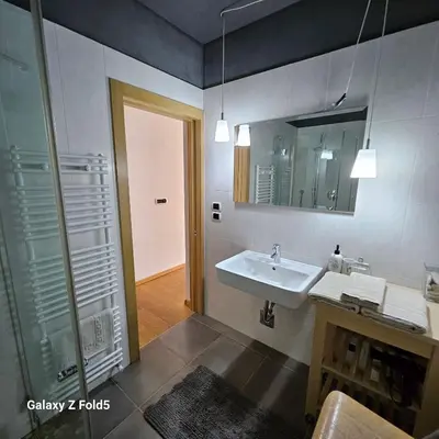 a bathroom with a sink and a shower and a mirror at Ka.La Apartment in Bolzano